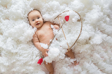 Cute smiling caucasian baby cupid on white clouds background with bow and heart arrow. Happy...