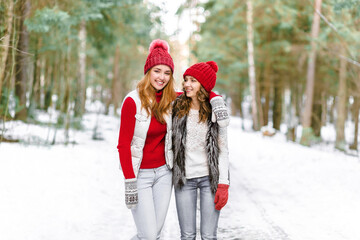 Two happy young women in snow, winter nature background.