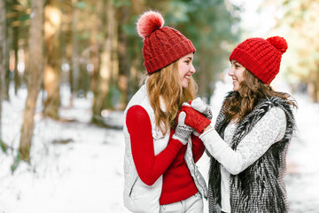 Two happy young women in snow, winter nature background.