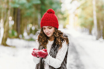 happy young woman holding a snowball on winter nature background.
