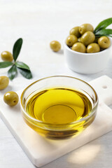 Glass bowl with fresh olive oil on white wooden table