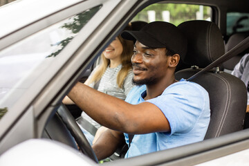 Cheerful young man driving car with friends on vacation