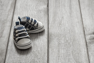 little baby sneakers on wooden background, cute small shoes on old wooden floor, the concept of the first steps of a baby, 1 year old