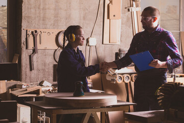 Adult carpenter congratulating teen boy after passing final practical exam