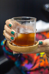 Joven sostiene un vaso de té helado con base de madera. Concepto de estilo de vida.