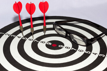 Poor vision concept, darts game, miss on target with darts and glasses