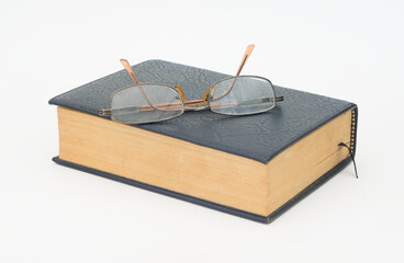 Glasses with antique book isolated on white.