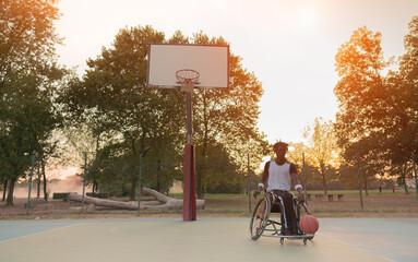 African basketball player in wheelchair having training in an outdoor park - Concept of...
