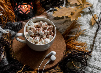 Cocoa with marshmallows, a cozy blanket, headphones on the bed. Autumn home cozy still life, top view