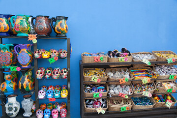 Display of Mexican crafts on a rack against a blue wall at a souvenir shop in Mexico