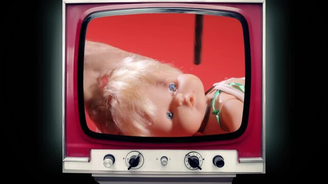 A retro TV set showing a scary horror clip: drilling a hole in the eye of a doll with an electric tool. Gross, weird, bizarre macro shot.
