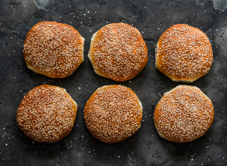Potato dough hamburger buns on a dark background, top view