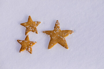 Fototapeta na wymiar Miniature gold polymer clay stars lie on pure white snow. New Year's photophone with place for text for postcards.