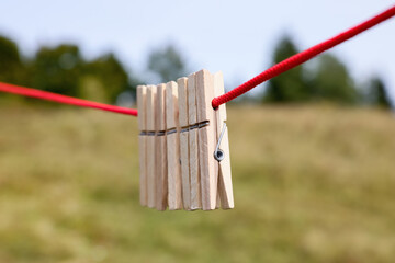Wooden clothespins hanging on washing line outdoors, closeup