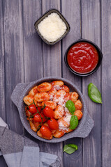 Gnocchi with tomatoes, red sauce, cheese and basil leaves