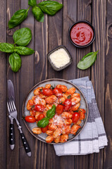 Gnocchi with tomatoes, red sauce, cheese and basil leaves