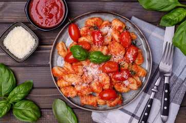 Gnocchi with tomatoes, red sauce, cheese and basil leaves