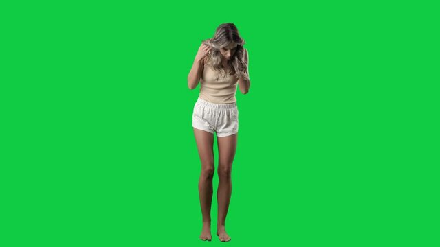 Woman in sleep wear looking down searching something dropped on the floor. Full body on green screen chroma key background