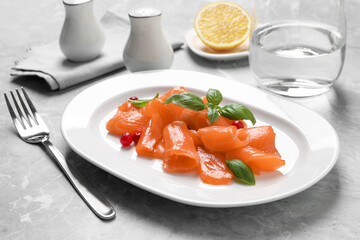 Salmon carpaccio with cranberries and basil served on grey table