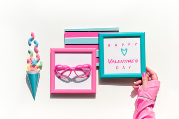 Happy Valentines day. Collection of vibrant objects and sweets in pink and mint green.Top view, flat lay. Chocolate, candy. Notebook, frame in hand. Festive geometric arrangement on white background.