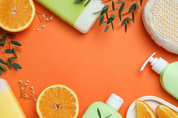 Flat lay composition with shower gel bottles and leaves on orange background, space or text