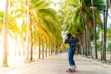 A young Asian man in a striped shirt and trousers is figure skating on a beach filled with coconut...