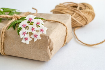 Eco friendly composition with gift box in craft reusable paper and  flower decor on white background. Holiday zero waste  concept.