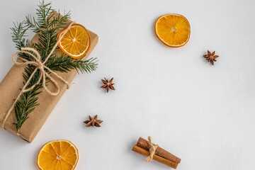 Eco friendly composition with gift boxes in craft reusable paper, cinamon, fir tree and oranges decor on white background. Holiday zero waste  concept.