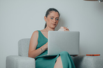 Mujer de negocios sentada en el sillón de su habitación haciendo una videollamada para una reunión de empresa de forma remota y online - obrazy, fototapety, plakaty