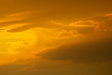 Naklejka na ściany i meble Autumn sky after rain in yellow-orange bright rays of the setting sun.