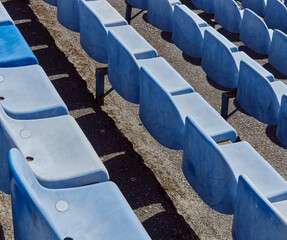 Obraz premium Rows of stadium grandstand seat. Rusty plastic blue and white stadium seat. Blue chairs in old stadium.