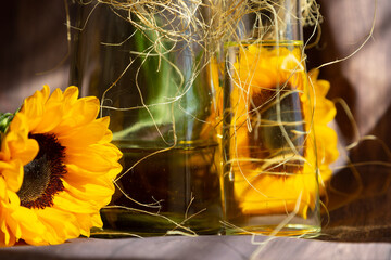 Botellas  de cristal con aceite en su interior  y  flores de girasol adornado con rafia 