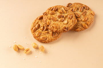 Cookies with roasted peanuts on top on beige background. View from above. Place for text.