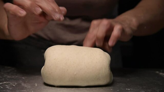 Close-up shot of bakery chef woman's hands kneading traditional recipe baking bread, on black background 4k footage. Slow motion