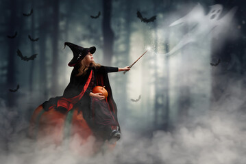 a girl in a witch costume sits on a pumpkin on Halloween wowing a magic wand catching a ghost....