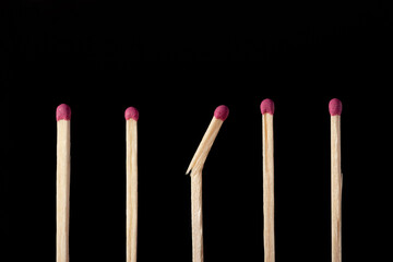 Row of matchsticks, all good, one broken in the middle. Close up shot of matches on black background, studio shooting.