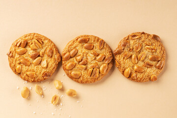 Cookies with roasted peanuts on top on beige background. View from above. Place for text.