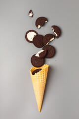 Ice cream cone with chocolate chip cookies with filling on gray background