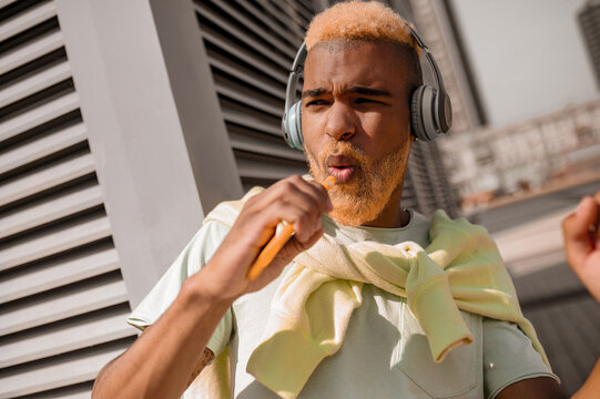 A young man in headphones listening to music and looking enjoyed