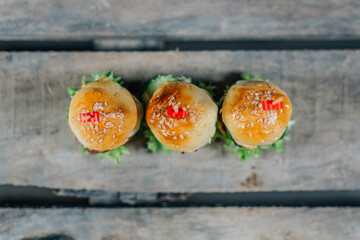 Top view of three mini burgers with beef, cheese, lettuce and cucumber. Fast food, party snacks...