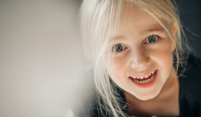 Happy smiling cute little girl with blonde hair and big blue eyes