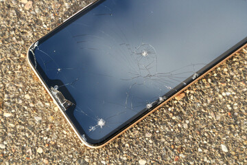 The smartphone fell to the asphalt and crashed. Cracks on the smartphone screen.