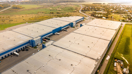 Aerial shot of industrial warehouse. Loading hub and many trucks with cargo trailers. Aerial view...