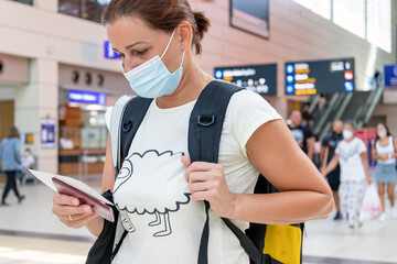 Young woman with face mask, passport and tickets at the International airport or railway station. Traveling concept in the time of covid 19 pandemic. 