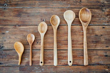 Wooden spoons of different sizes and lengths lie on the table. There are six spoons in total.