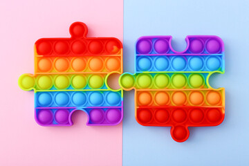 Popit toy in the form of a puzzles on a colorful background. Multicolored Pop it toy