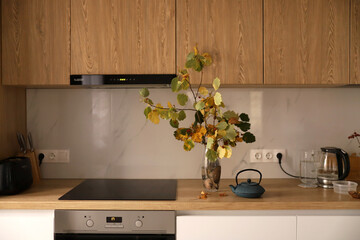 Bright interior, vase with yellow flowers stands on a wooden table in a white modern kitchen. 