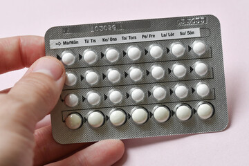 A woman holding full chart of birth control pills