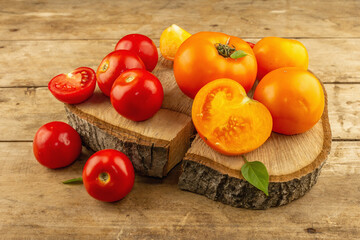 Assorted ripe tomatoes on a wooden stand. Fresh red and orange organic vegetables