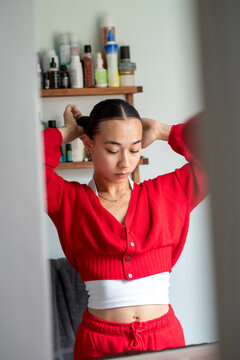 UK, London, Woman in red clothing doing hair in front of mirror